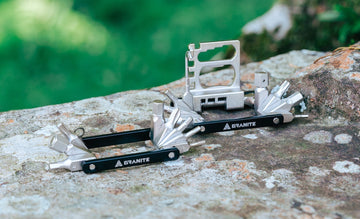 Granite Design Diverse 10 and Diverse 20 multi-tools with chain breaker attachment, displayed outdoors on a textured stone surface with a blurred green background.