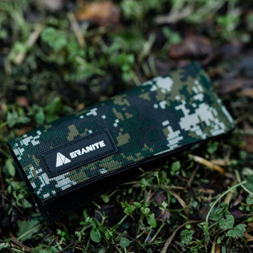 Granite rocknroll tool roll in camo green resting on grass, ideal for carrying bike repair essentials in rugged outdoor settings.