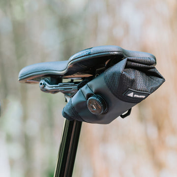 Granite Quiver saddle bag securely attached beneath a bicycle seat, showcasing a compact design with a dial closure system for easy access and adjustment.