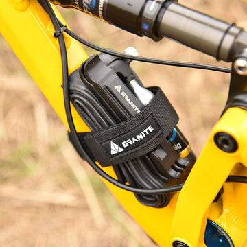 Granite Rockband strap in black securely holds a Talon tire lever and spare tube on a yellow bike frame, providing a compact storage solution for riders.