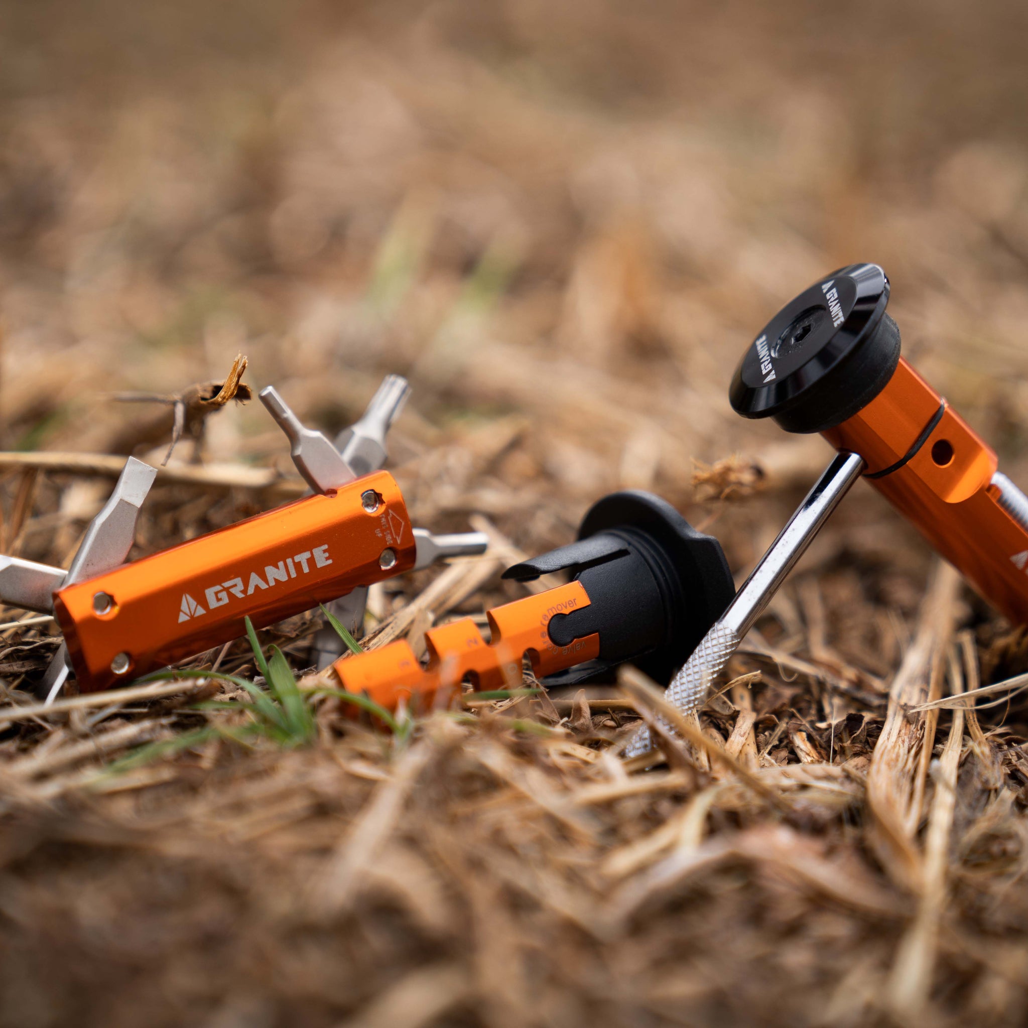 Granite multitool and Granite Stash chain tool placed on dry grasses