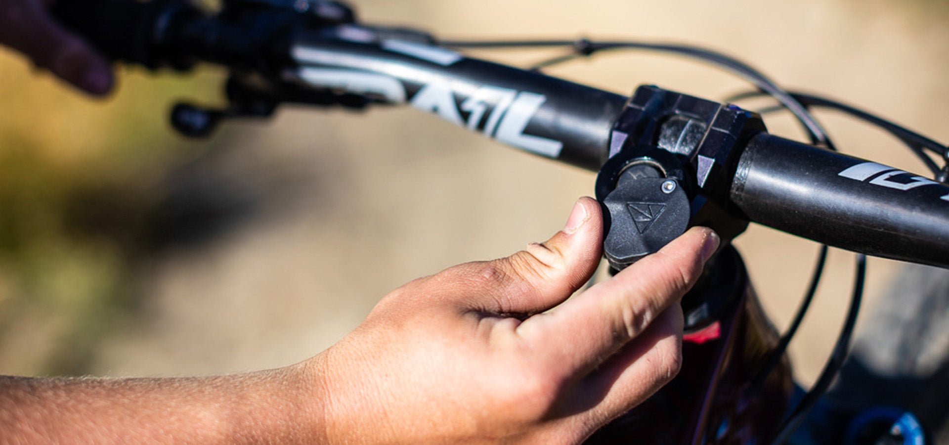 Close-up of a hand adjusting a Stash RT multi bike tool integrated into the handlebar on a sunny day.