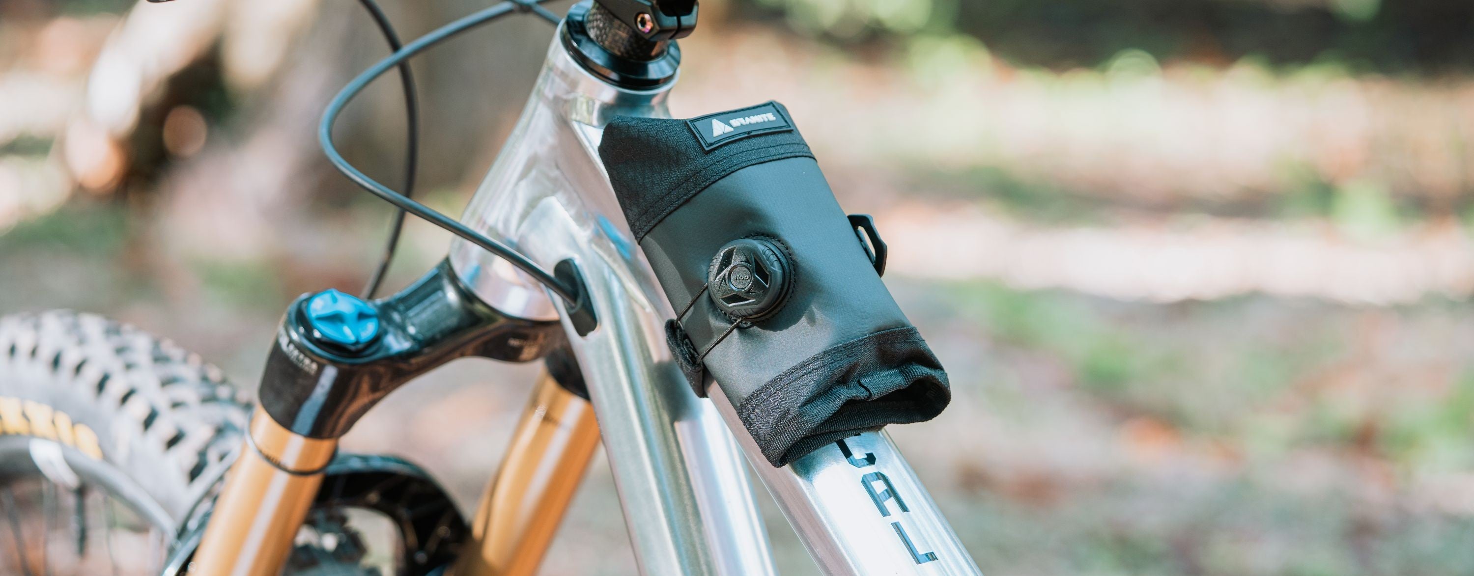 Bicycle with a Granite Quiver bike bag mounted on the frame top tube against a blurred natural background