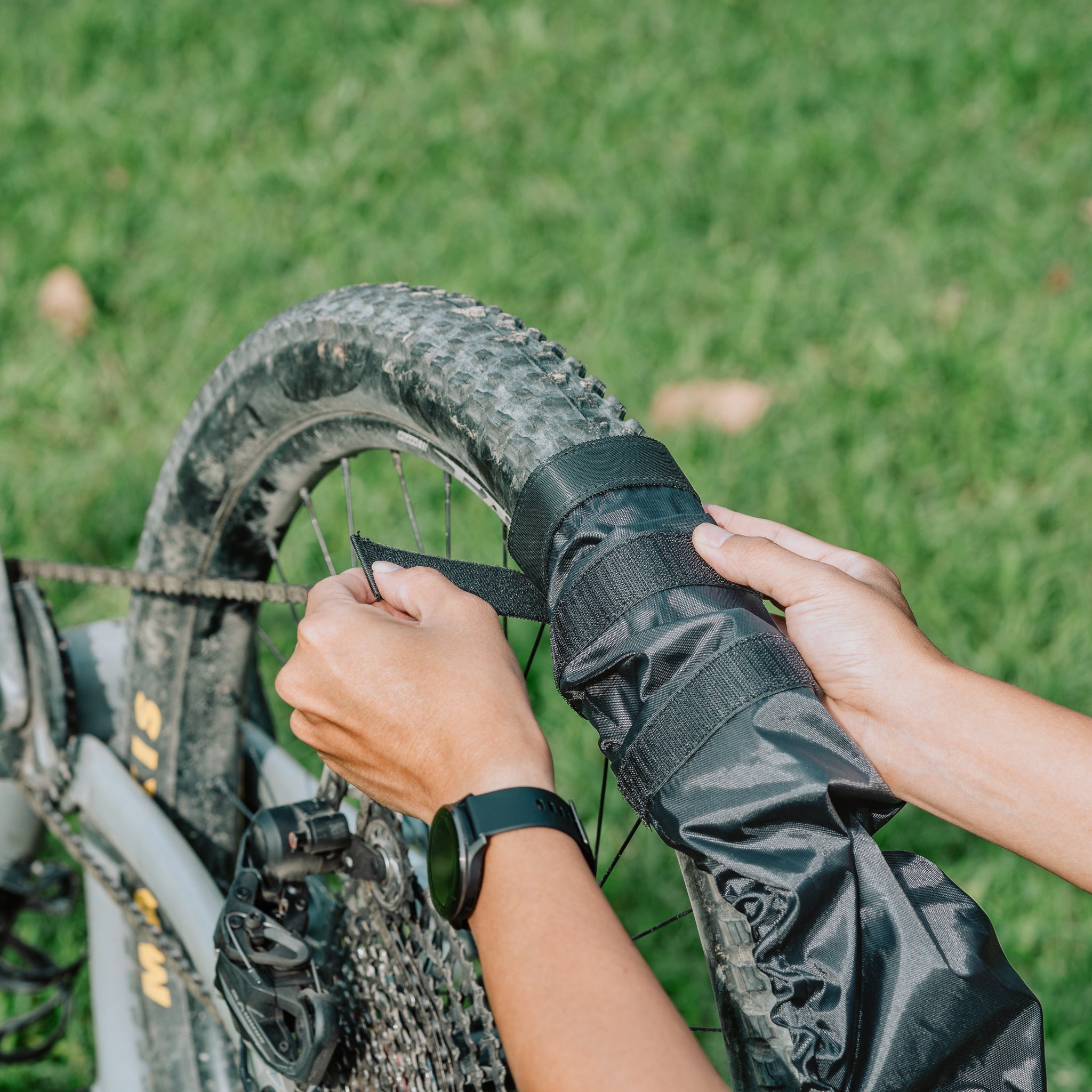 Person fasten a Granite Crust tire onto a wheel on a grassy background.