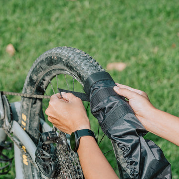 Person fasten a Granite Crust tire onto a wheel on a grassy background.