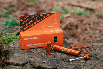 Two portable Granite Suture Aero tire plug kits on a wooden surface with foliage.