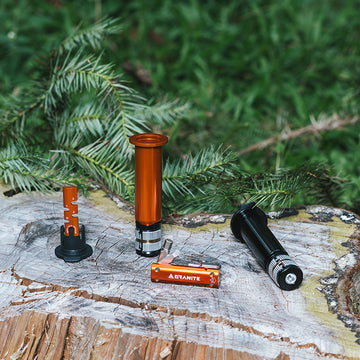 Collection of Granite Stash RCX bike tools displayed on a wooden surface, featuring an orange and black design amidst green foliage.