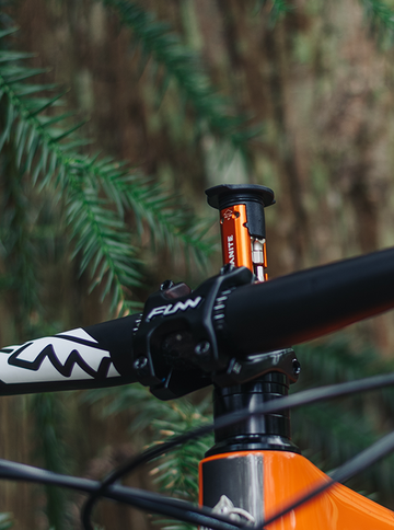 Close-up of a bike's steerer tube showing a Granite Stash multi tool inserted, highlighting its vibrant orange color against the black components.