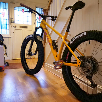 Yellow bicycle with Granite Crust tire covers inside a house.