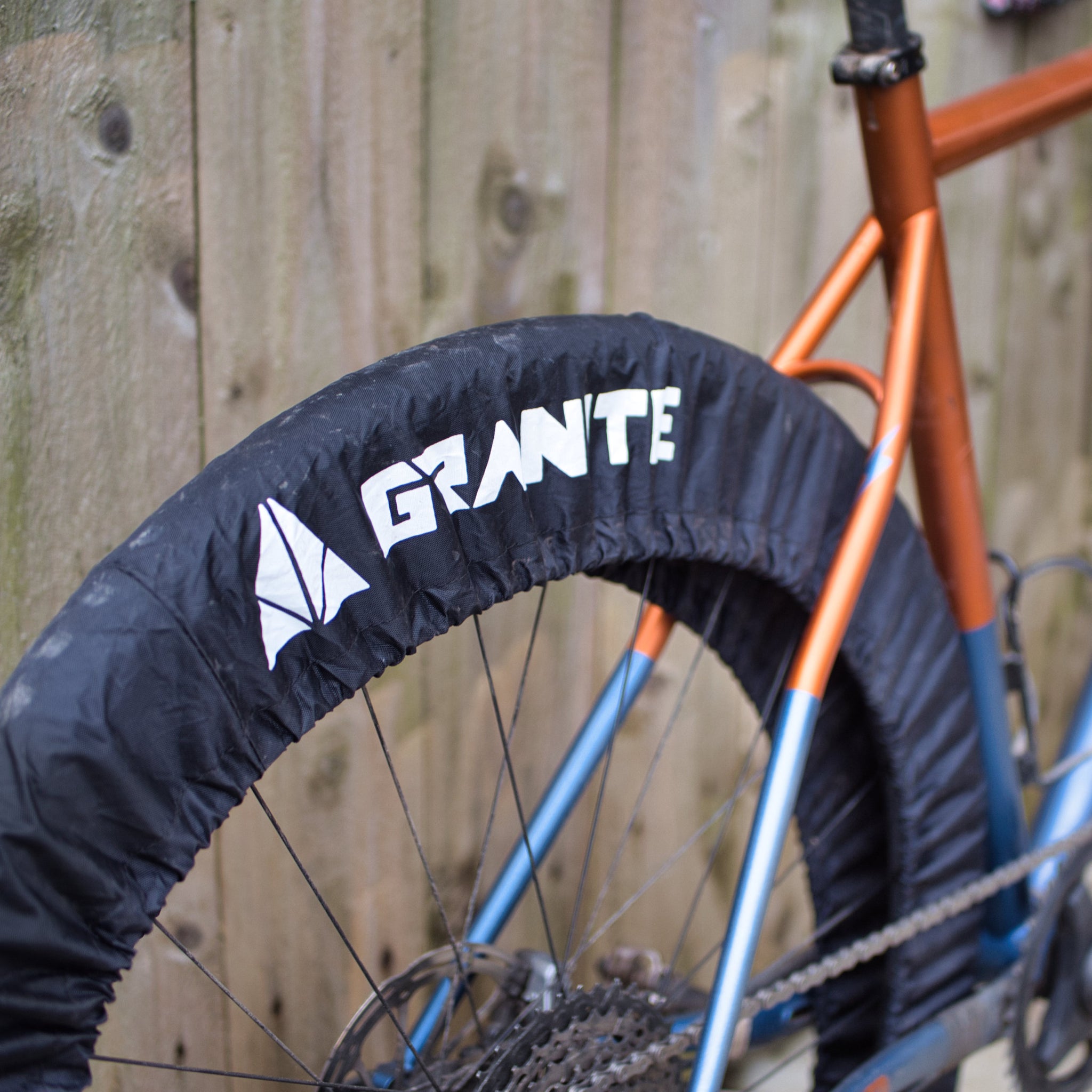 Bicycle wheel with a Granite Crust tire cover featuring 'Granite' branding against a wooden fence background.