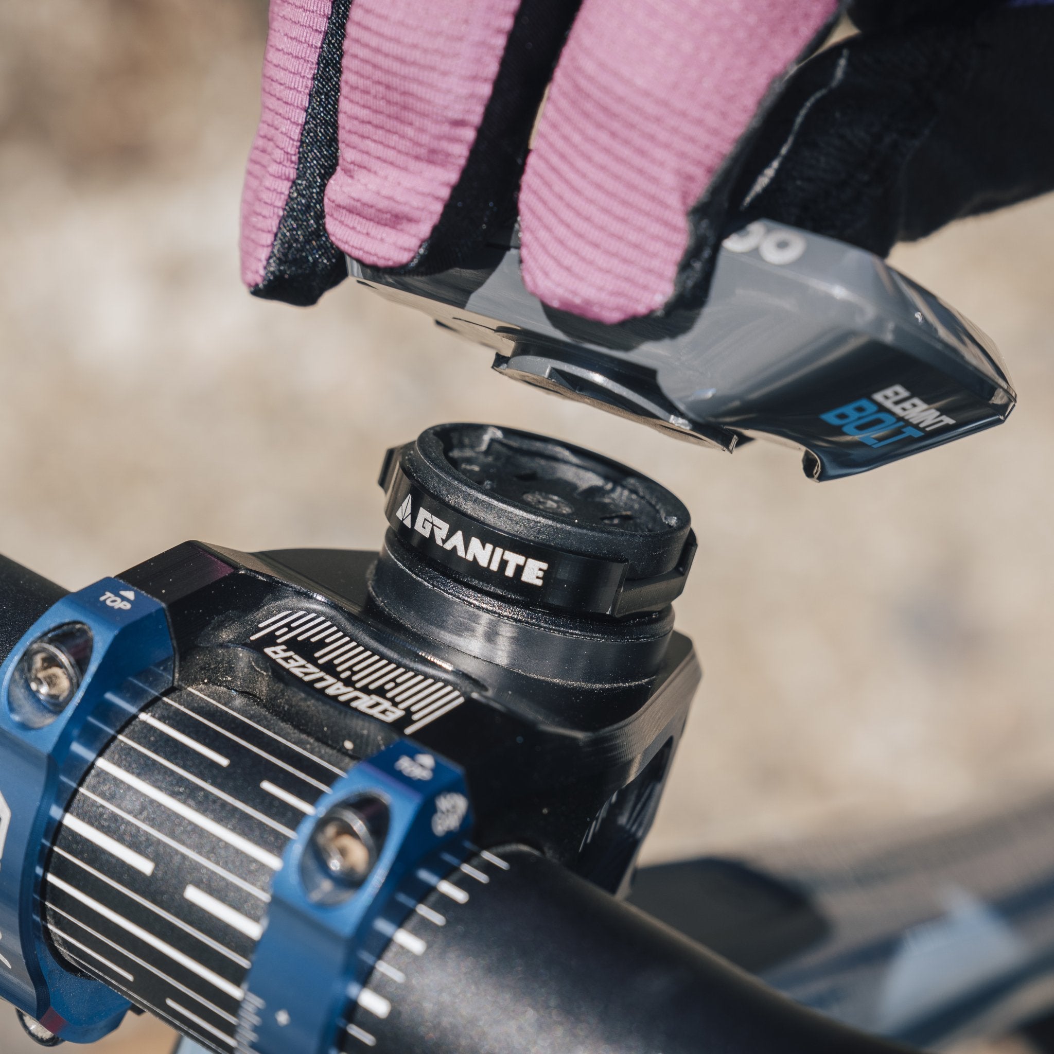 Hand attaching an Wahoo bike computer to the Granite Scope Mount on a bike's handlebar stem, secured for optimal readability.