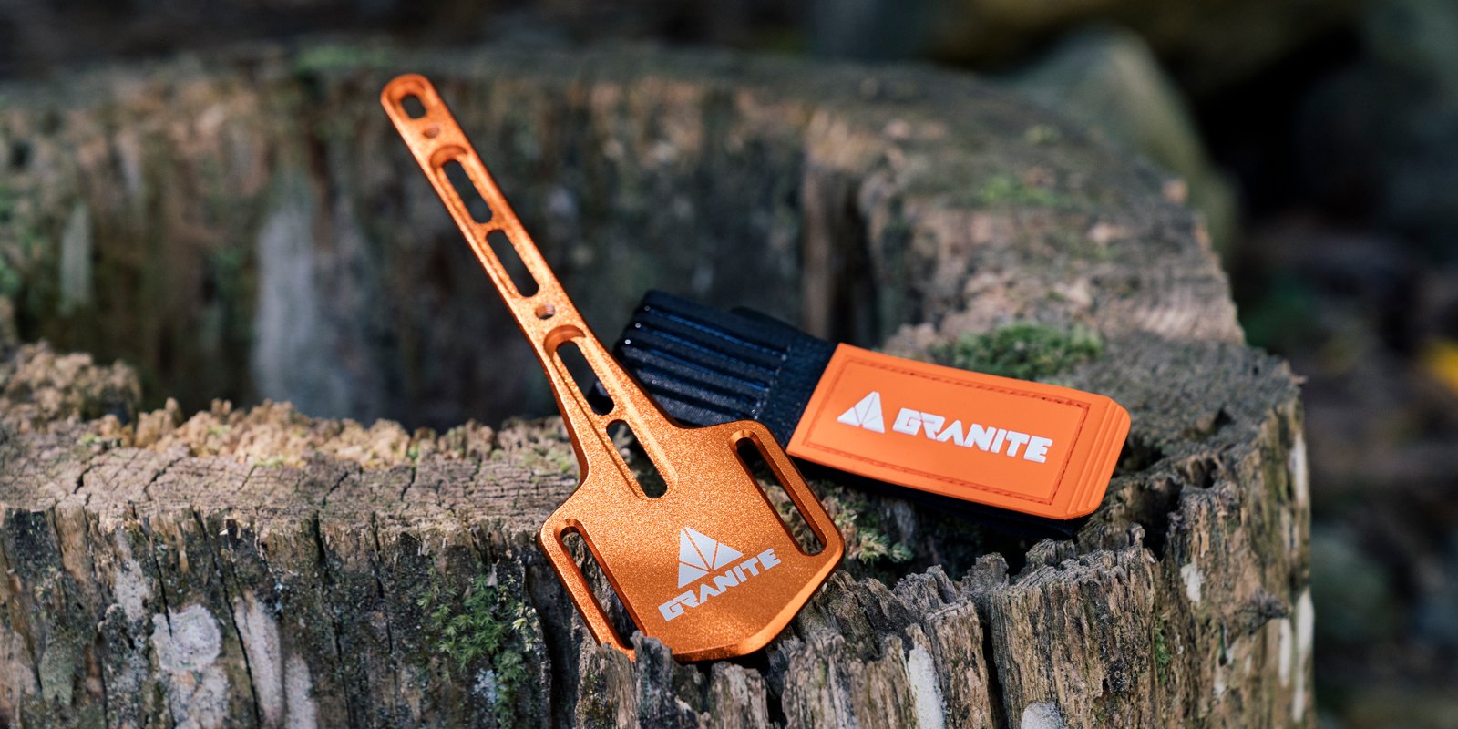 Granite portaledge XE mounting plate and strap placed on a tree stump, ideal for attaching tools securely during outdoor rides.