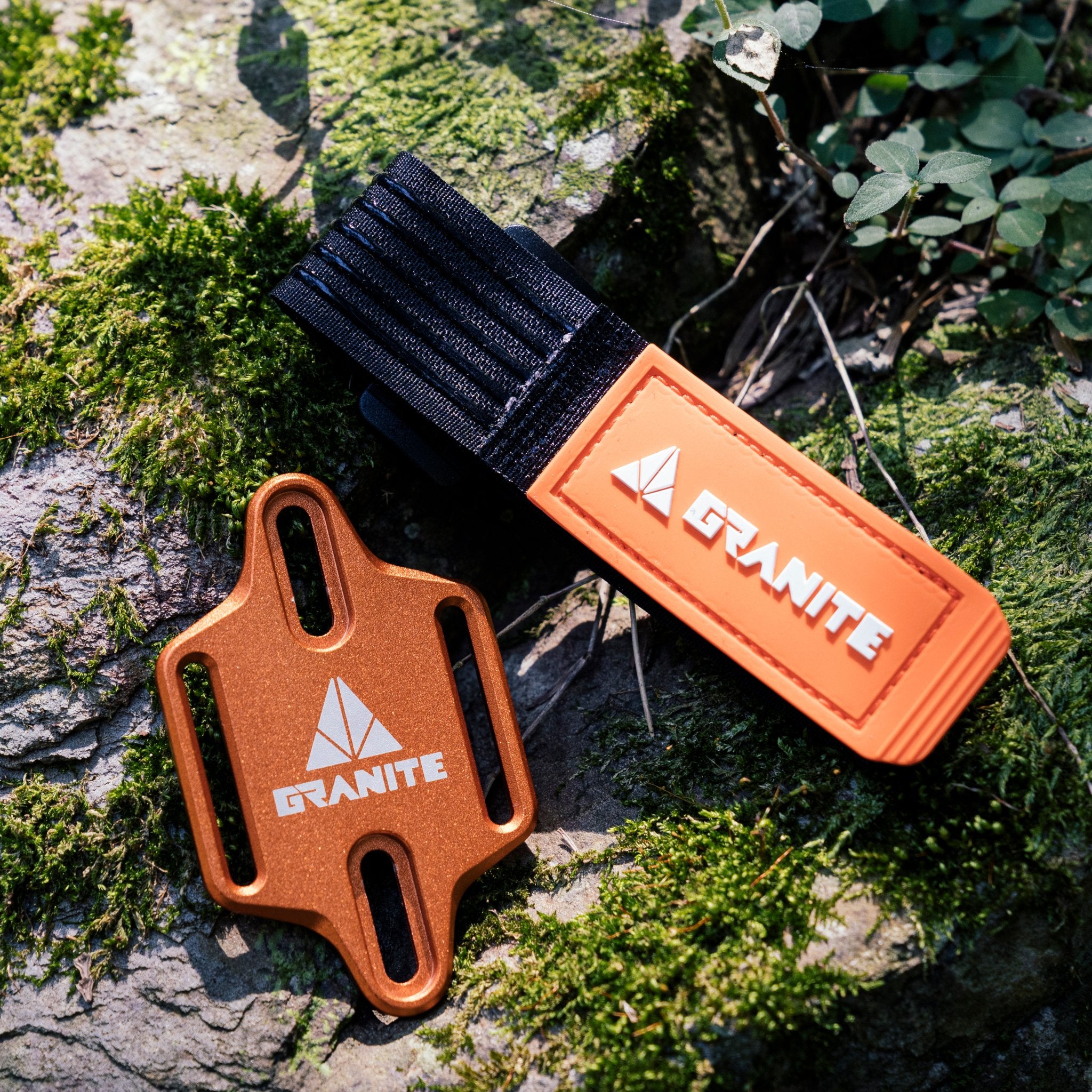 Granite Portaledge strap and mounting plate displayed on a moss-covered rock, ideal for secure attachment on outdoor rides.