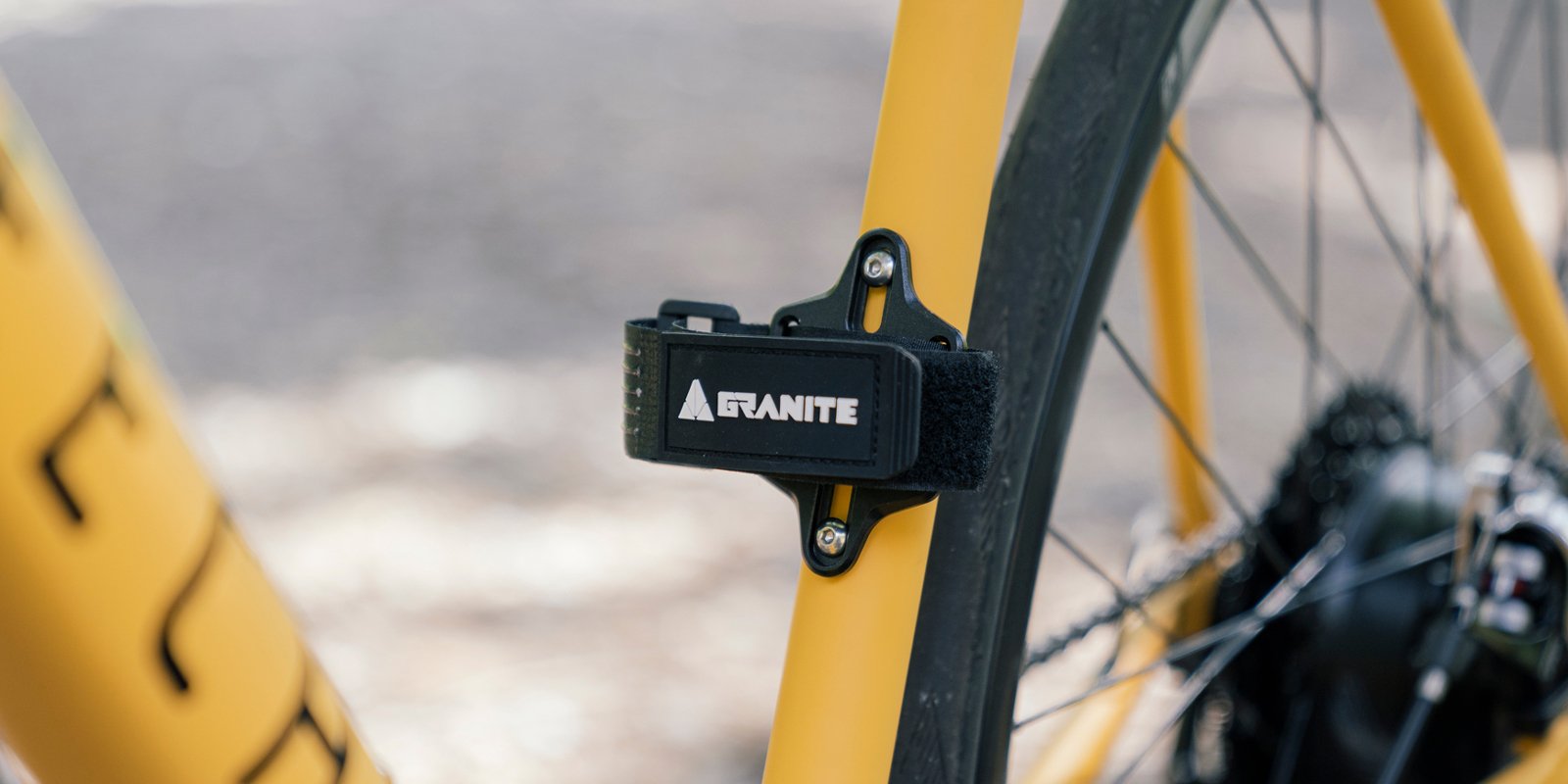 Granite Portaledge strap kit attached to a yellow bike's bottle bosses, providing secure storage for tools or tubes during rides.