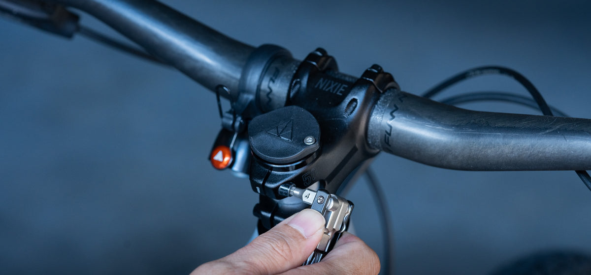 Hand using the Granite Diverse 10 multi tool on a mountain bike stem against a dark background