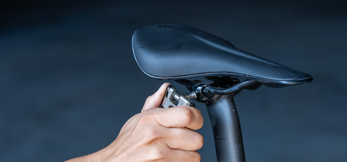 Hand using the Granite Diverse 20 multi tool on a seatpost clamp under a black saddle