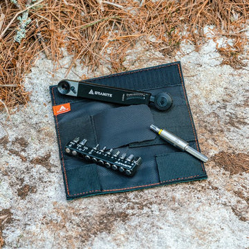 Granite Rocknroll tq tool kit with a torque ratchet wrench, bit holder, and pouch laid out on a textured rocky surface.