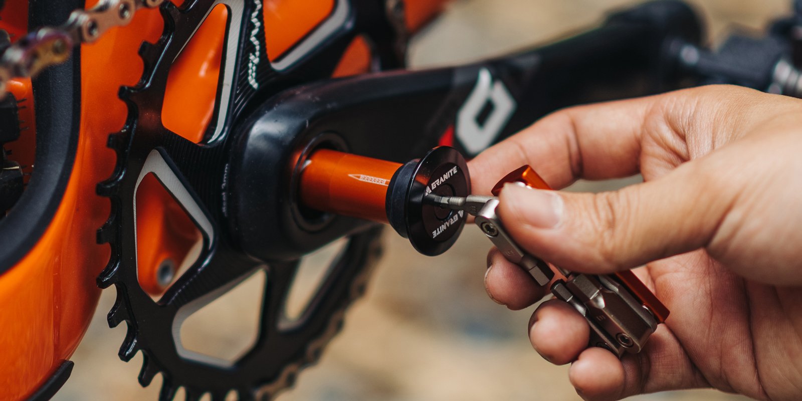 A close-up of a cyclist using a Stash multitool to insert a Stash tyre plug into the bike's crankset.