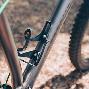 Granite Aux Carbon Bottle Cage securely mounted on a bicycle frame, positioned on the downtube.