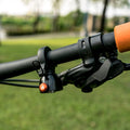 Granite Cricket Bell mounted on bike handlebar near brake lever in an outdoor setting.