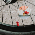 Red Granite Juicy Nipple Schrader valve cap on a bike wheel with inset showing cap flipped to remove the valve core.