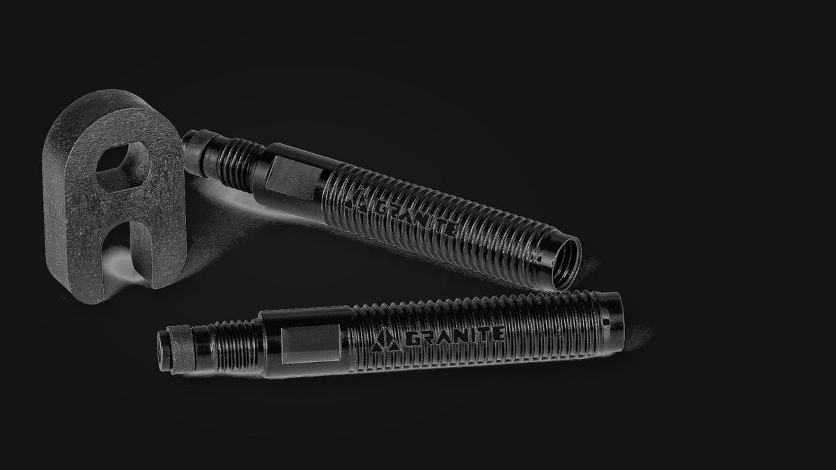 Two black Granite Presta valve extenders and the valve core tool on a dark background