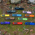 Assorted Granite Rockband frame straps in various colors arranged on mossy ground with rocks and fallen leaves.