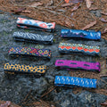 Assorted Granite Rockband plus frame straps in various colorful patterns, arranged on rocky ground with pine needles.