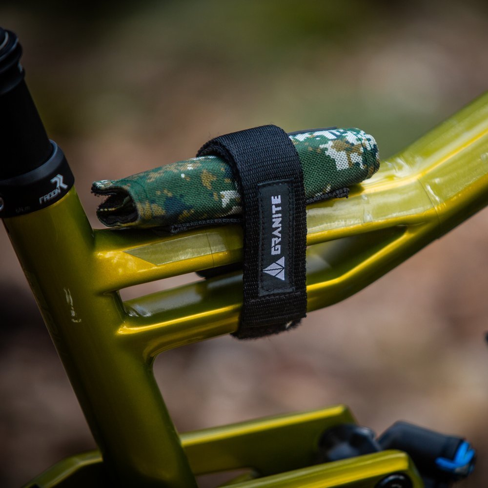 Rocknroll Mini Ratchet Tool Kit in Black secured with a black Rockband carrier strap to the frame of a green mountain bike.