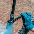 Gloved hand using Granite TQ torque wrench on bike seat post for precise adjustments.