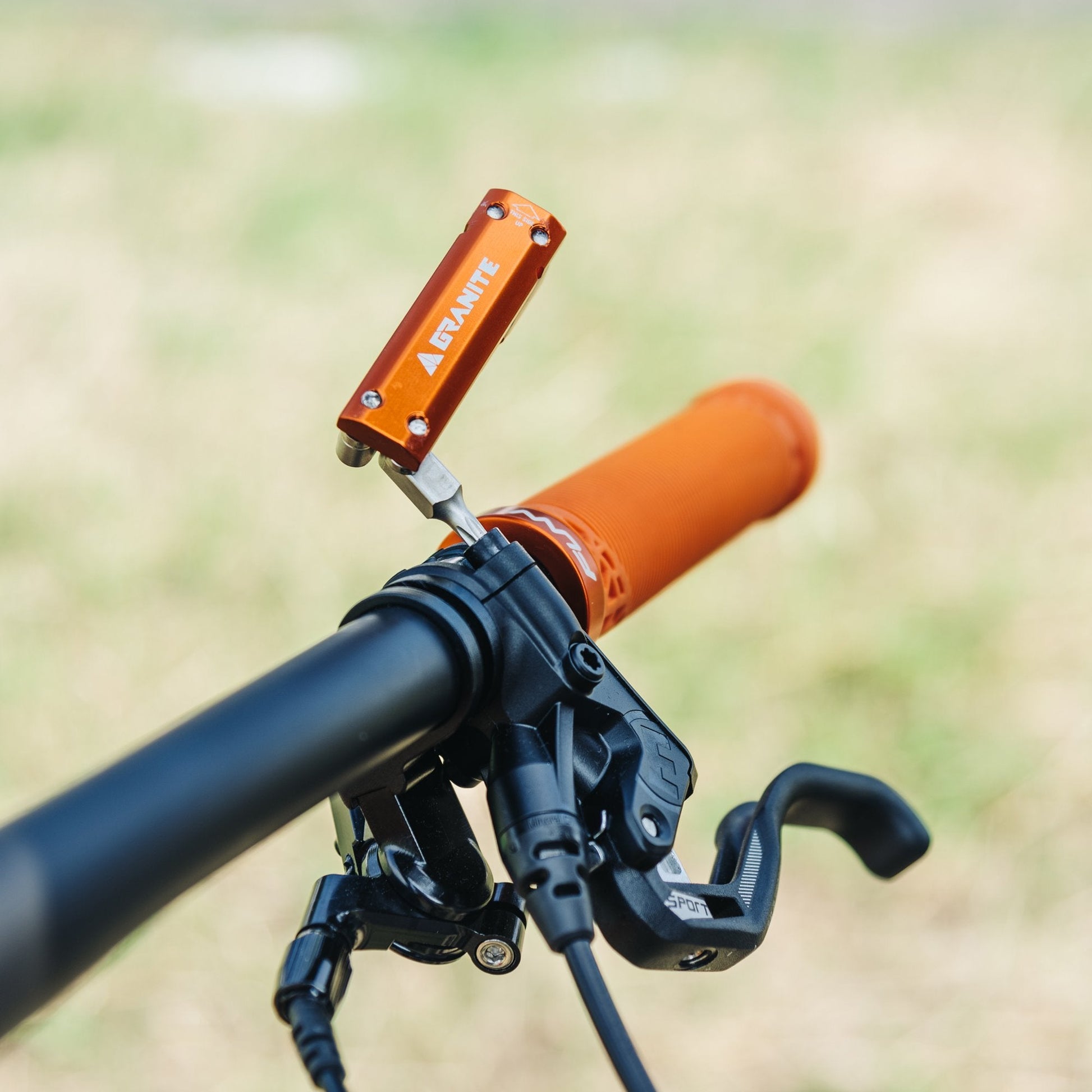 The hex wrench of Granite Stash multitool with 8-piece multi-tool is tightening the bolt on a bike handlebar.