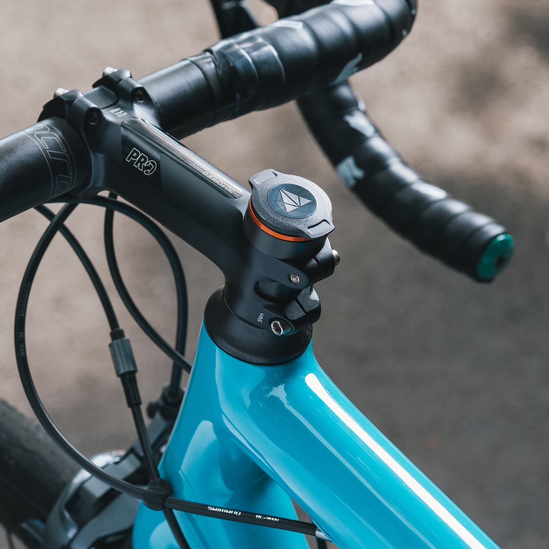 Close-up of a bike handlebar stem with a Granite RCX multitool cap integrated into the top, on a blue bike frame.