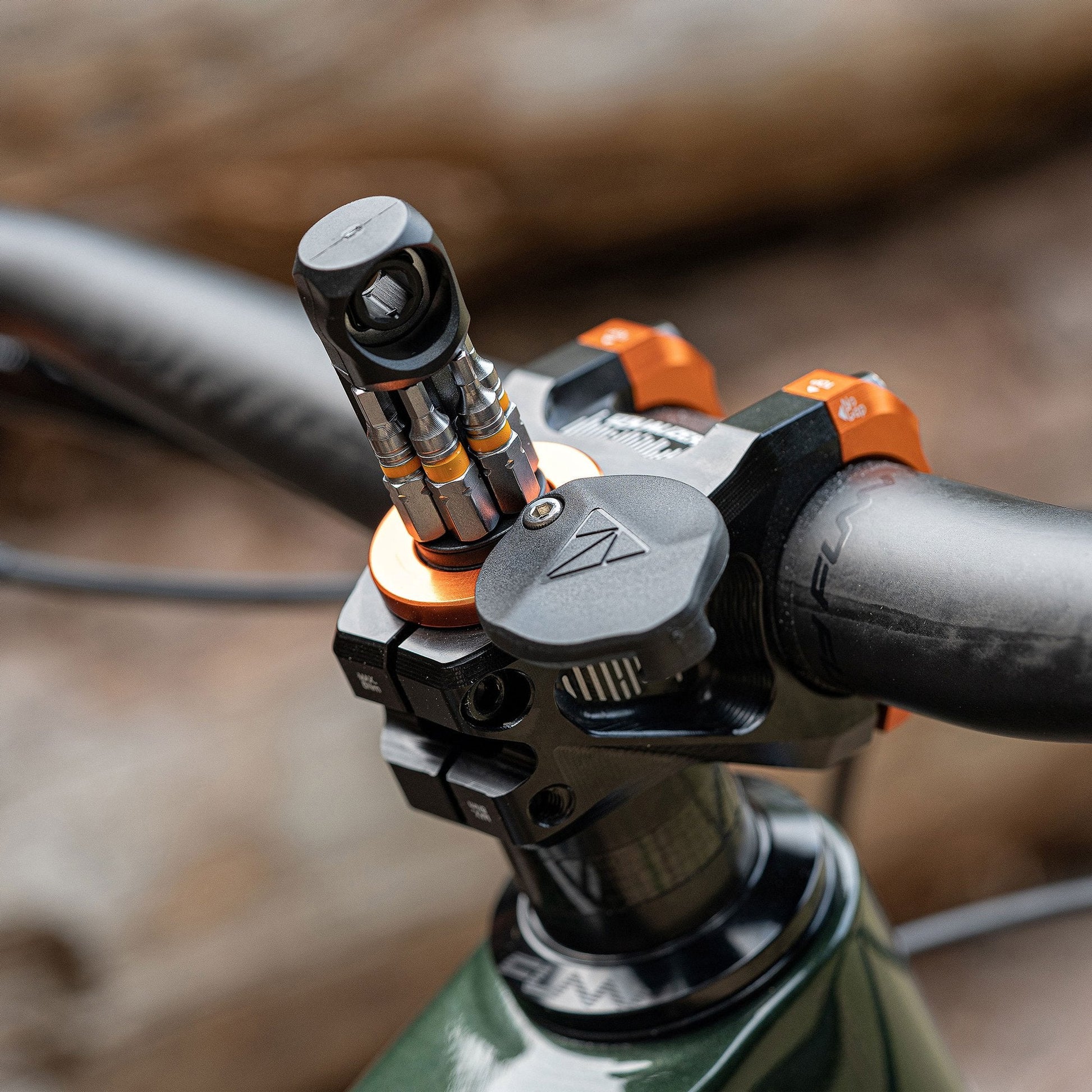 Granite Stash RT Ratchet Tool Kit in orange mounted on a bike's handlebar stem, displaying tool bits in a compact setup.