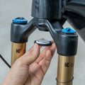 Installing an Airtag onto a bike's front suspension fork using a mount, showcasing secure and discreet tracking integration.