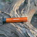 Granite Stash Tubeless Flat Tire Repair Kit in orange, resting on a textured tree bark.