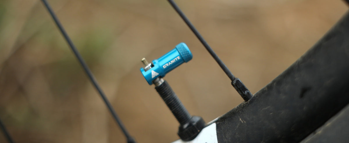 Blue Granite Juicy Nipple cap on a black 44 mm tubeless Presta valve stem fitted to a bike rim