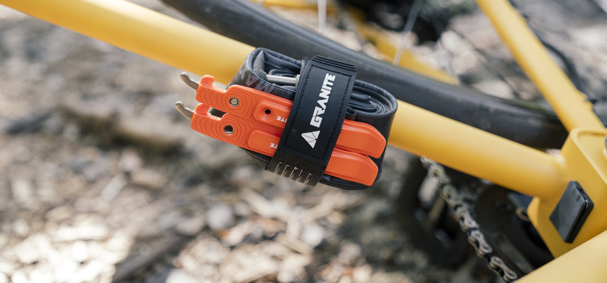 Granite Portaledge strap holding a spare tube and orange tire levers on a yellow mountain bike frame