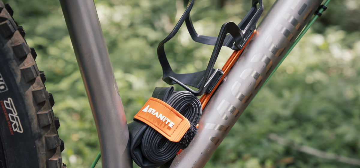 Orange Granite Portaledge XE under a bottle cage with a spare tube strapped below on a titanium bike frame