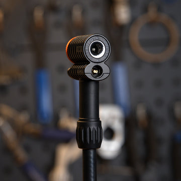 Granite Quickie pump head on a floor pump hose, Presta and Schrader ports facing the camera, workshop tool wall behind