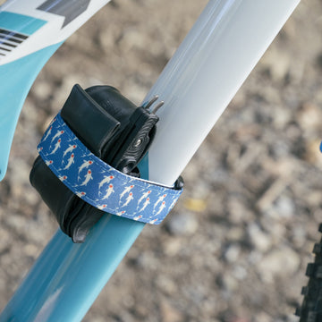 Blue koi-print Rockband+ holding a spare tube and tool on a light blue bike frame