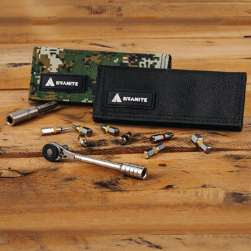 A compact Granite ratchet tool, several interchangeable bits, and two Granite-branded tool pouches—one camouflage and one black—are displayed on a wooden surface.