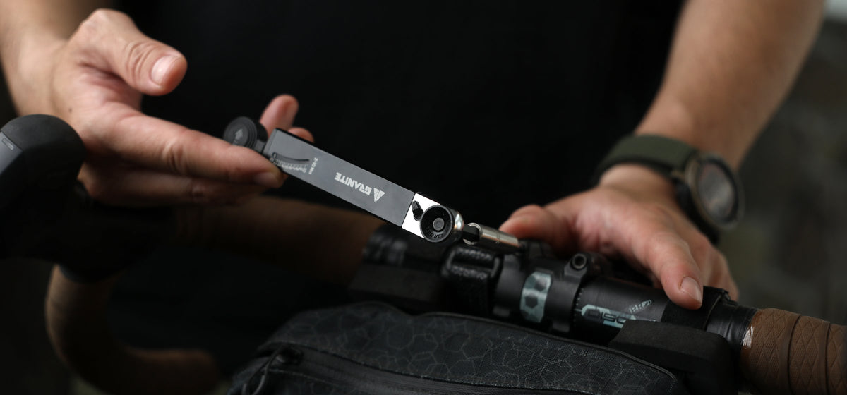 Hands using the Granite Rocknroll TQ torque ratchet on the stem of a drop-bar gravel bike