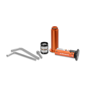 The Granite Stash RCX kit laid out on white: orange multi-tool, orange tool housing, silver expander plug, an M6 bolt and two hex keys