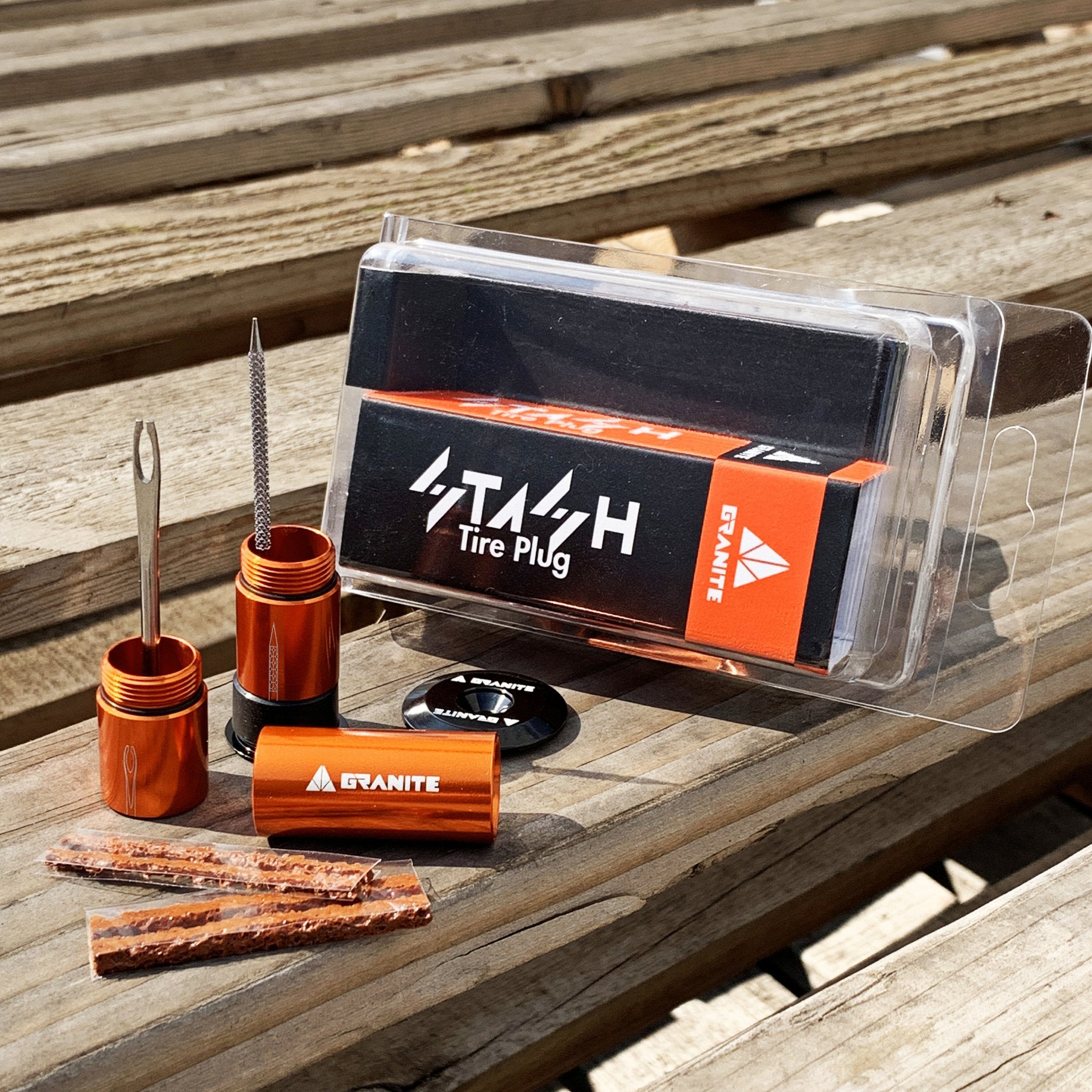 A display of the Granite Stash Tire Plug kit, featuring orange aluminum tools and tire plugs on a wooden surface.